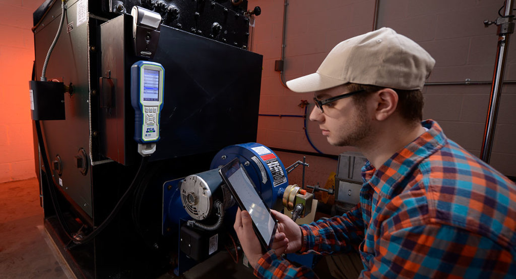 当使用PCA 400燃烧和排放分析仪调试商用锅炉时，技术人员检查平板上的测量值。
